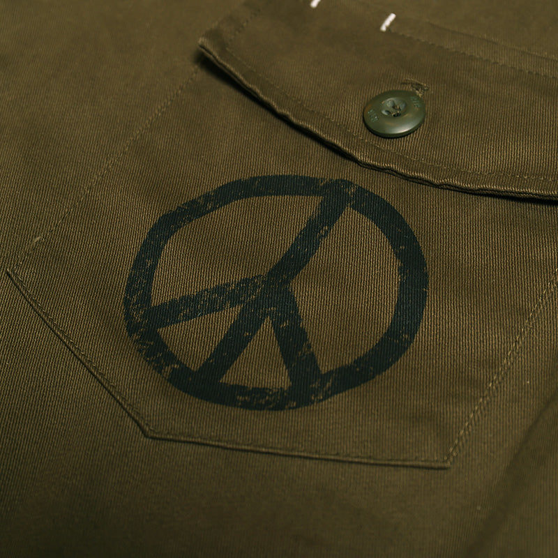 Olive drab chest pocket flap with peace symbol patch and green button