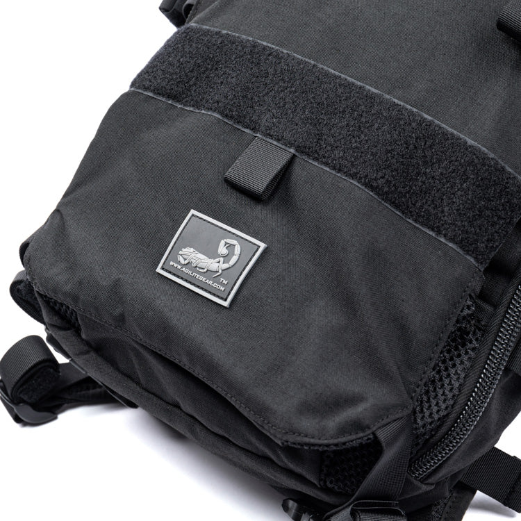 Dark assault backpack with front flap, hook-and-loop patch, and side zipper pocket