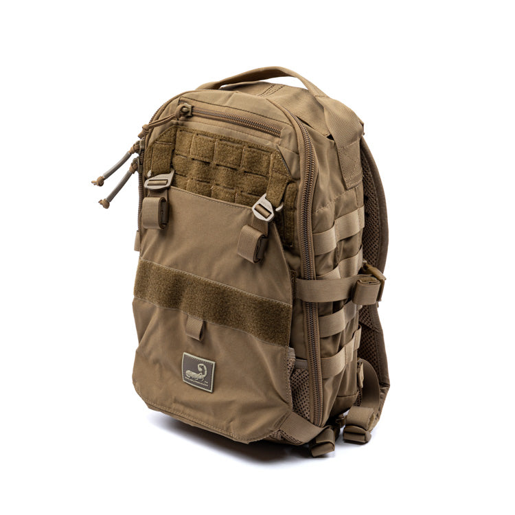 Tan assault pack with side storage pouches, front zip pocket, and mesh backing
