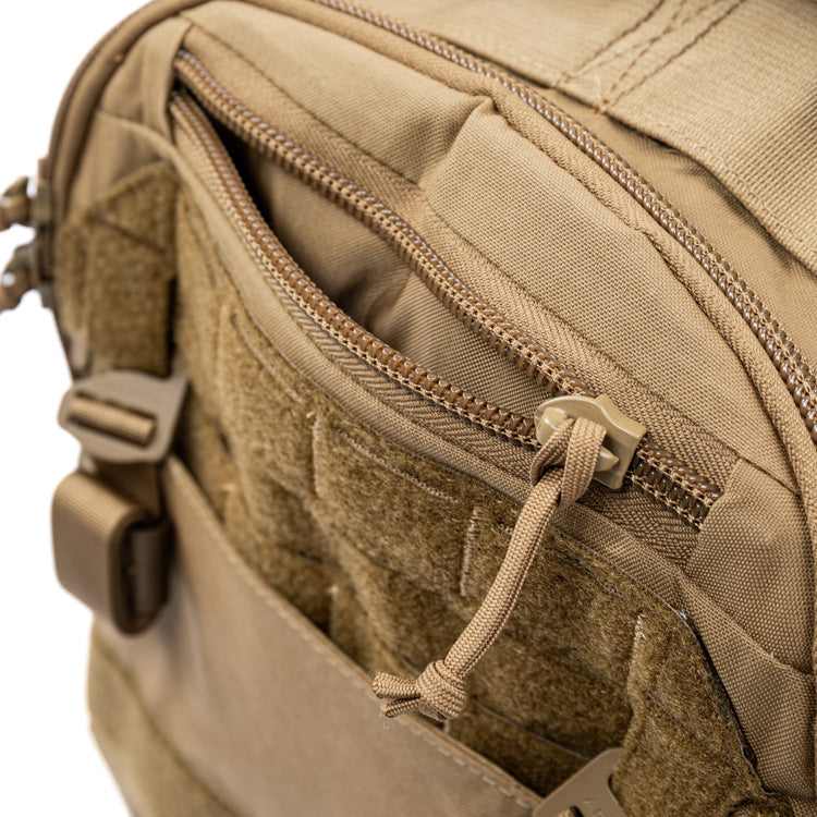 Tan assault pack close-up of zip track, stitching, and front mesh pocket